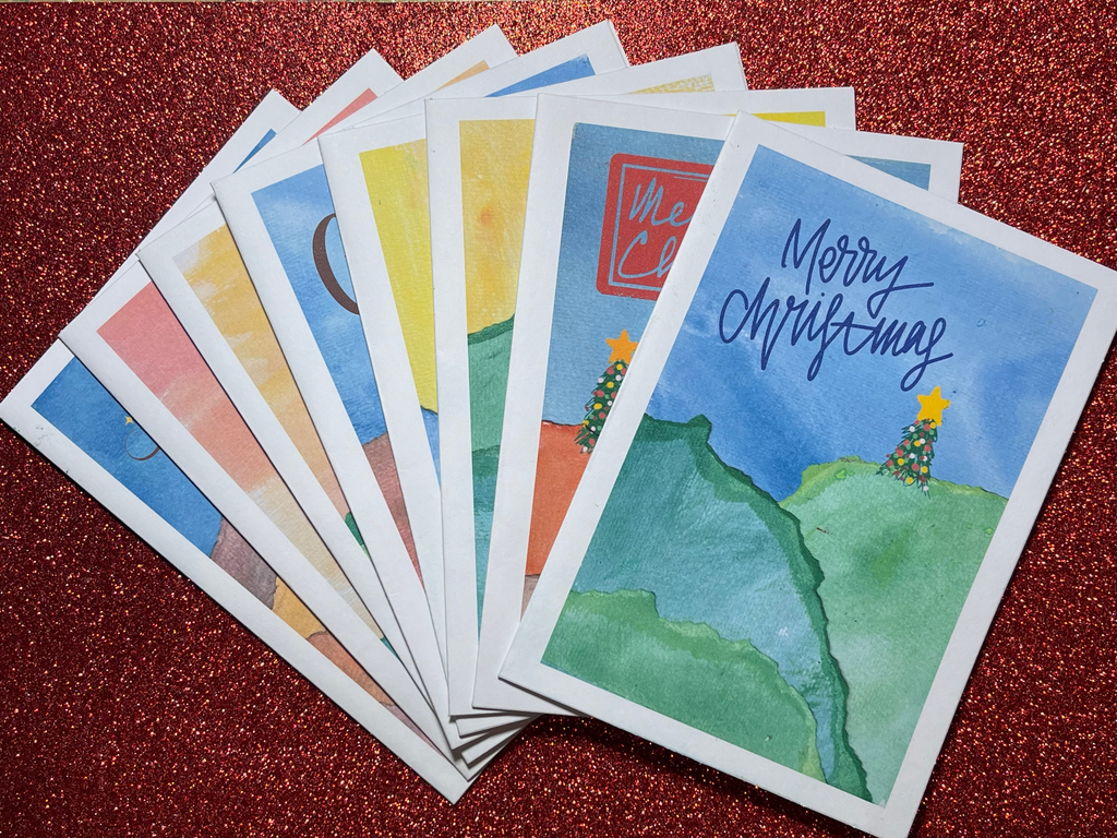 Stack of colorful postcards with scenic illustrations on a red textured surface